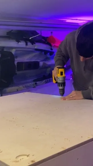 Drilling a cabinet panel under purple light