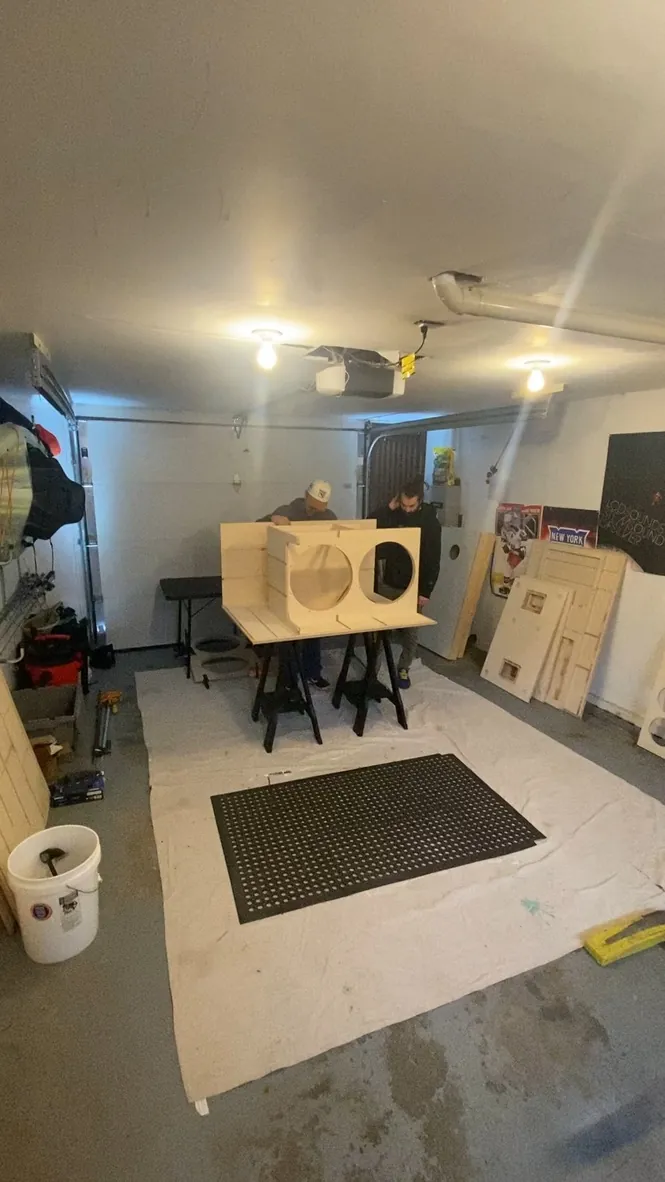 Two crew members assembling a cabinet in a garage workshop