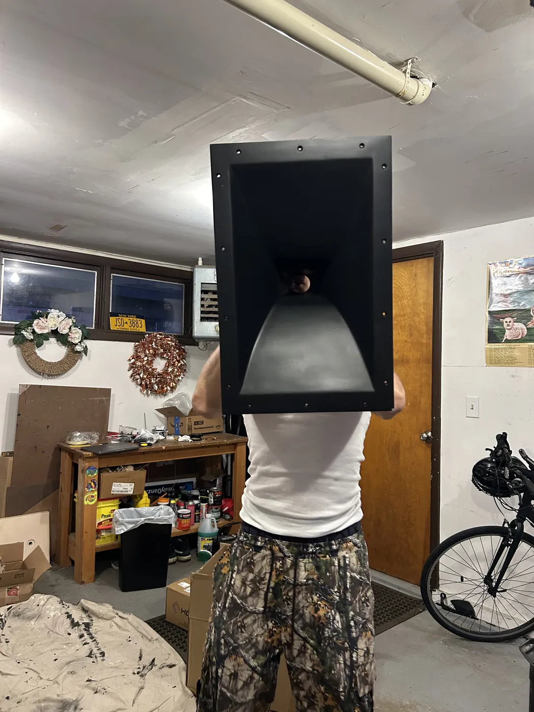 A crew member holding a horn up in front of his face in the garage