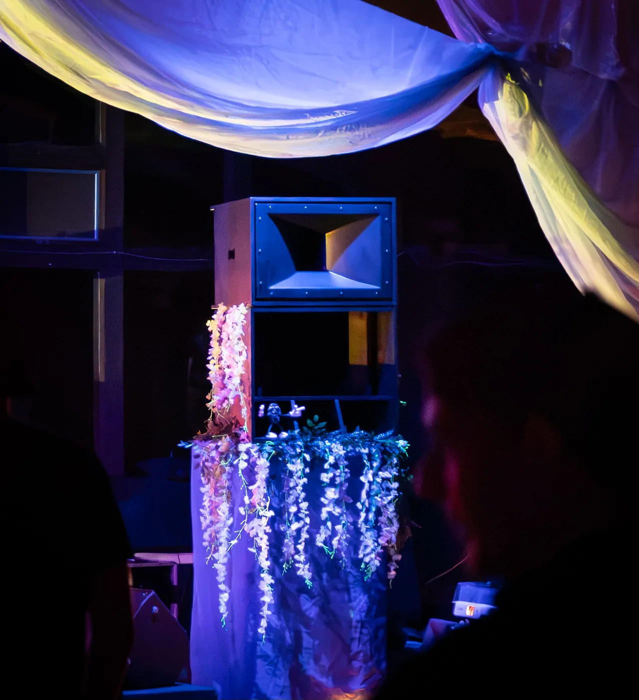 A horn top on a flower-covered stand under purple stage lights